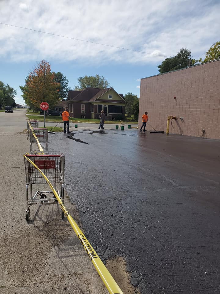 workers sealing asphalt for business parking lot